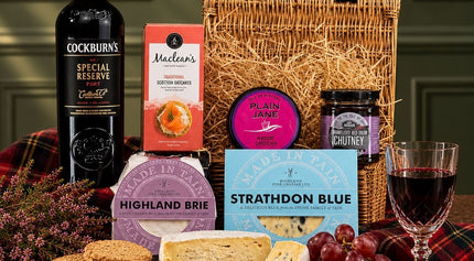 Port and cheese hamper with Scottish cheese truckles, blue cheese, oatcakes and chutney in a wicker basket.