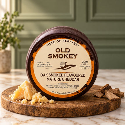 Isle of Kintyre Old Smokey mature cheddar truckle with crumbled cheese on a wooden serving board.