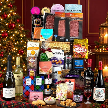 Scottish Festive Feast Hamper with cheese, smoked meats, biscuits, sweets, wine, prosecco and port beside a Christmas tree.