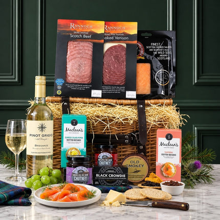 White wine hamper with Scottish cheese, charcuterie, oatcakes and savoury snacks in an open wicker basket.