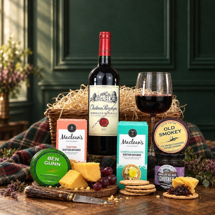 Red wine and Scottish cheese hamper with oatcakes and chutney, styled with cheese wedges and grapes.