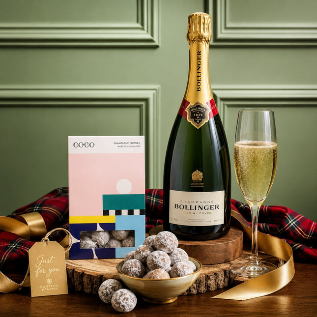 Bollinger champagne bottle with a glass, chocolates, and a gift box on a wooden surface.
