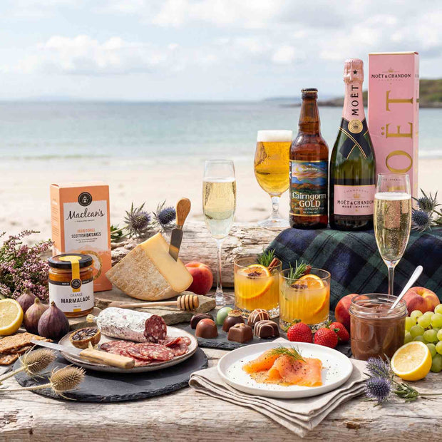 Outdoor setting with food, drinks, and Mouton Cadet products by the sea.