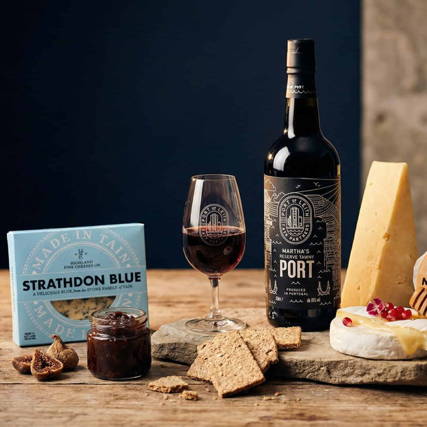 Luxury Scottish birthday hamper with port wine, artisan cheeses, oatcakes and chutney beautifully presented on a warm elegant background
