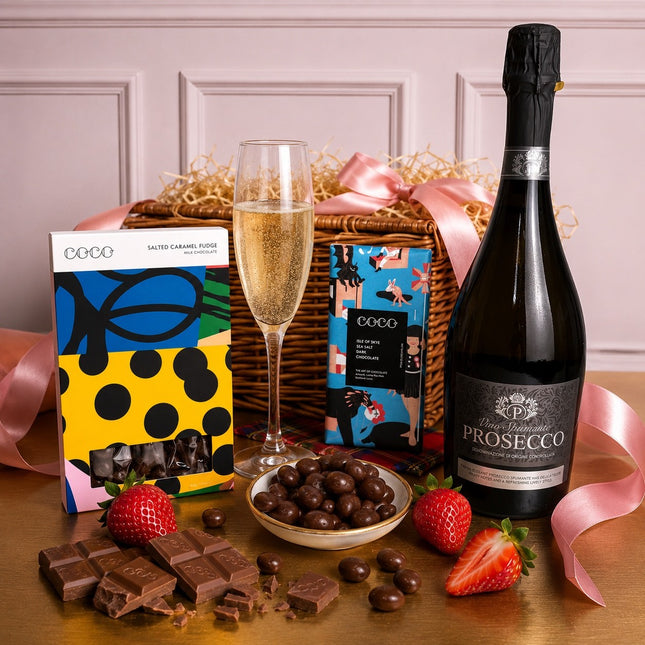 Prosecco bottle, chocolate treats, and strawberries on a table with a decorative background.